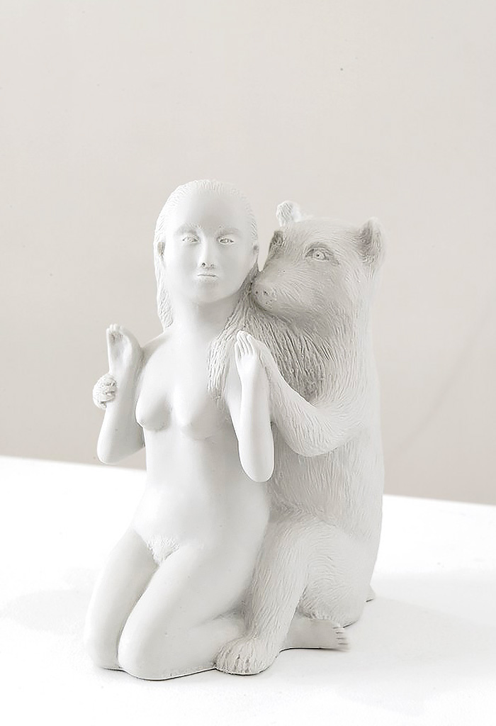 La sculpture en porcelaine blanche représente une femme nue agenouillée, tandis qu'un ours se tient affectueusement derrière elle, l'enlaçant par les épaules. Fidèle au travail de Kiki Smith, cette pièce explore la relation intime, spirituelle et mythologique entre le corps humain (souvent féminin) et le monde animal ou la nature sauvage. Des reproductions ou répliques inspirées de ce style de sculpture narrative (souvent associées à des contes de fées ou de la mythologie) se trouvent sur des plateformes comme Amazon.